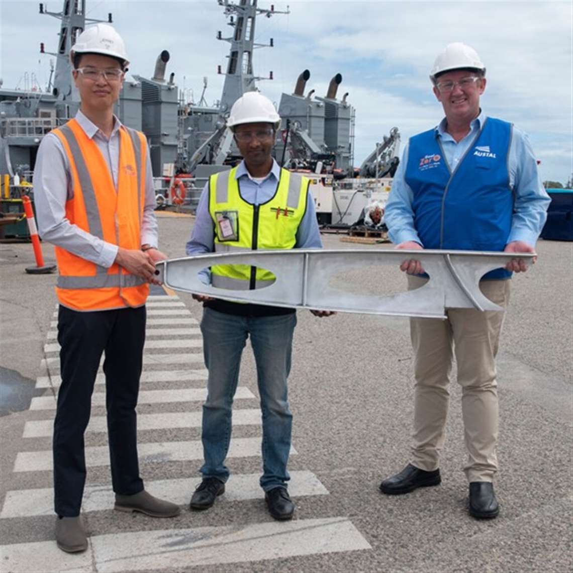 Austal technology project manager, Jeffrey Poon; DNV representative Jude Stanislaus; and AML3D chief executive officer Andrew Sales holding one of the davit crane component parts