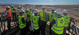 A group of construction professionals in hi-vis vests and hard hats survey progress on a site in Neom, Saudi Arabia